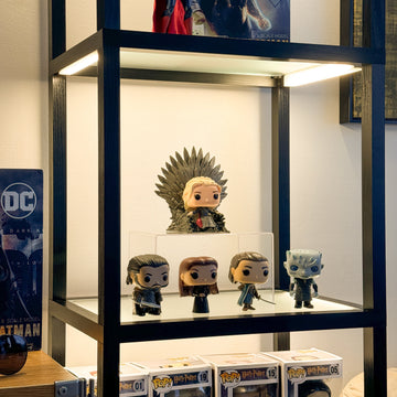 Collectible figures lit from above on a glass shelf of the FENLO Fantasy Plus PRO display shelf with lights
