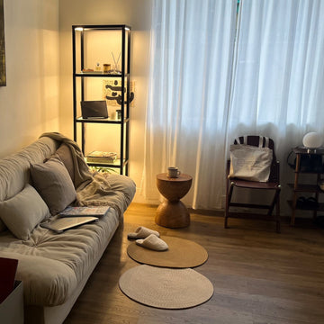 FENLO floor lamp with shelves glowing warm beside a sofa in a living room